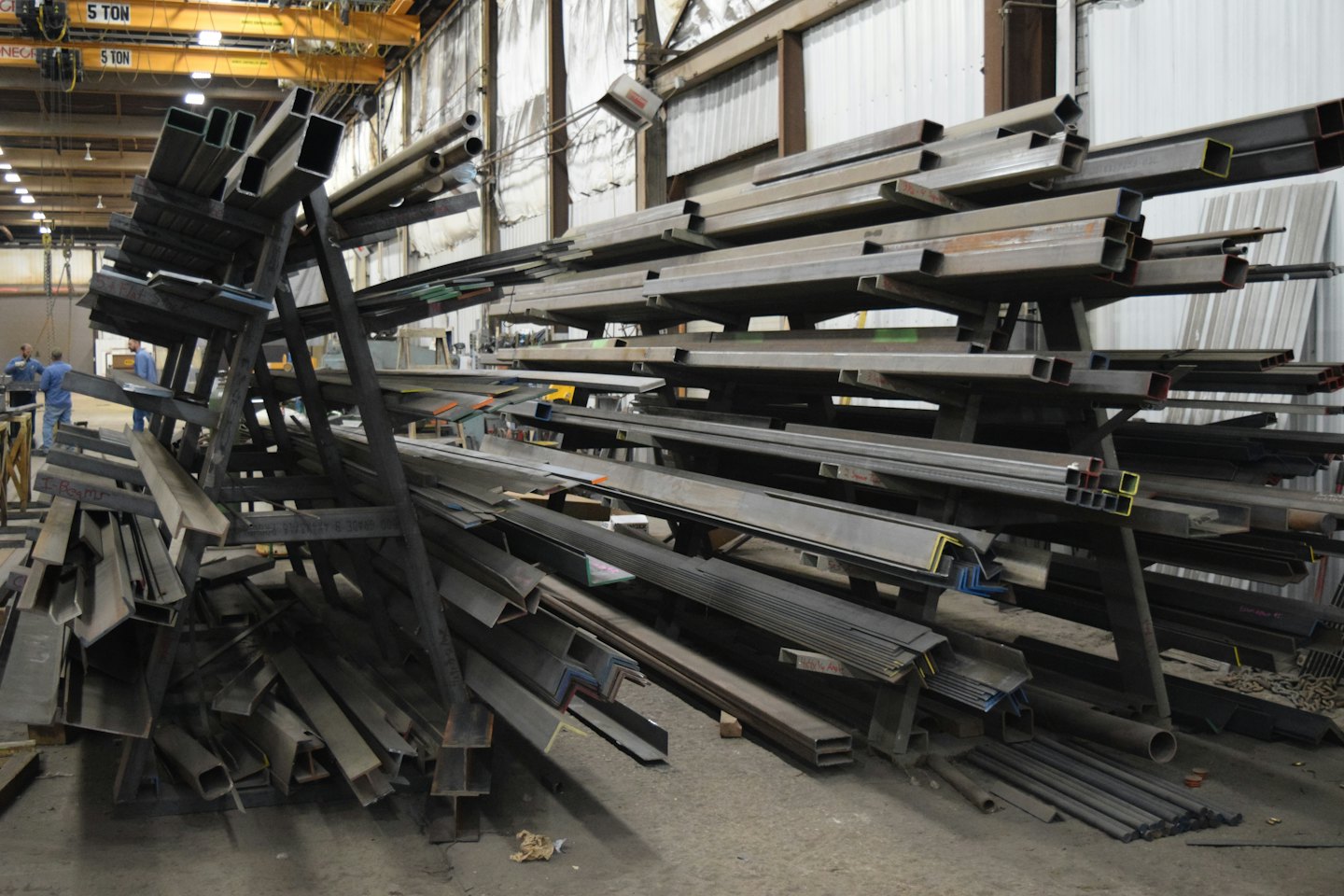 Metal de stock, incluyendo vigas, perfiles y tuberías en estanterías de almacén.