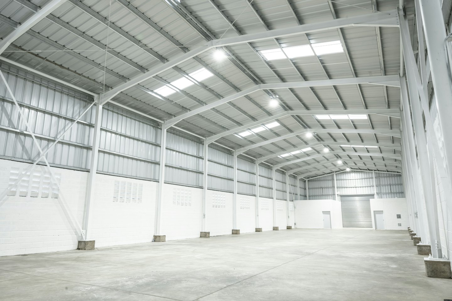 Almacén industrial vacío con techos altos y pisos de concreto.